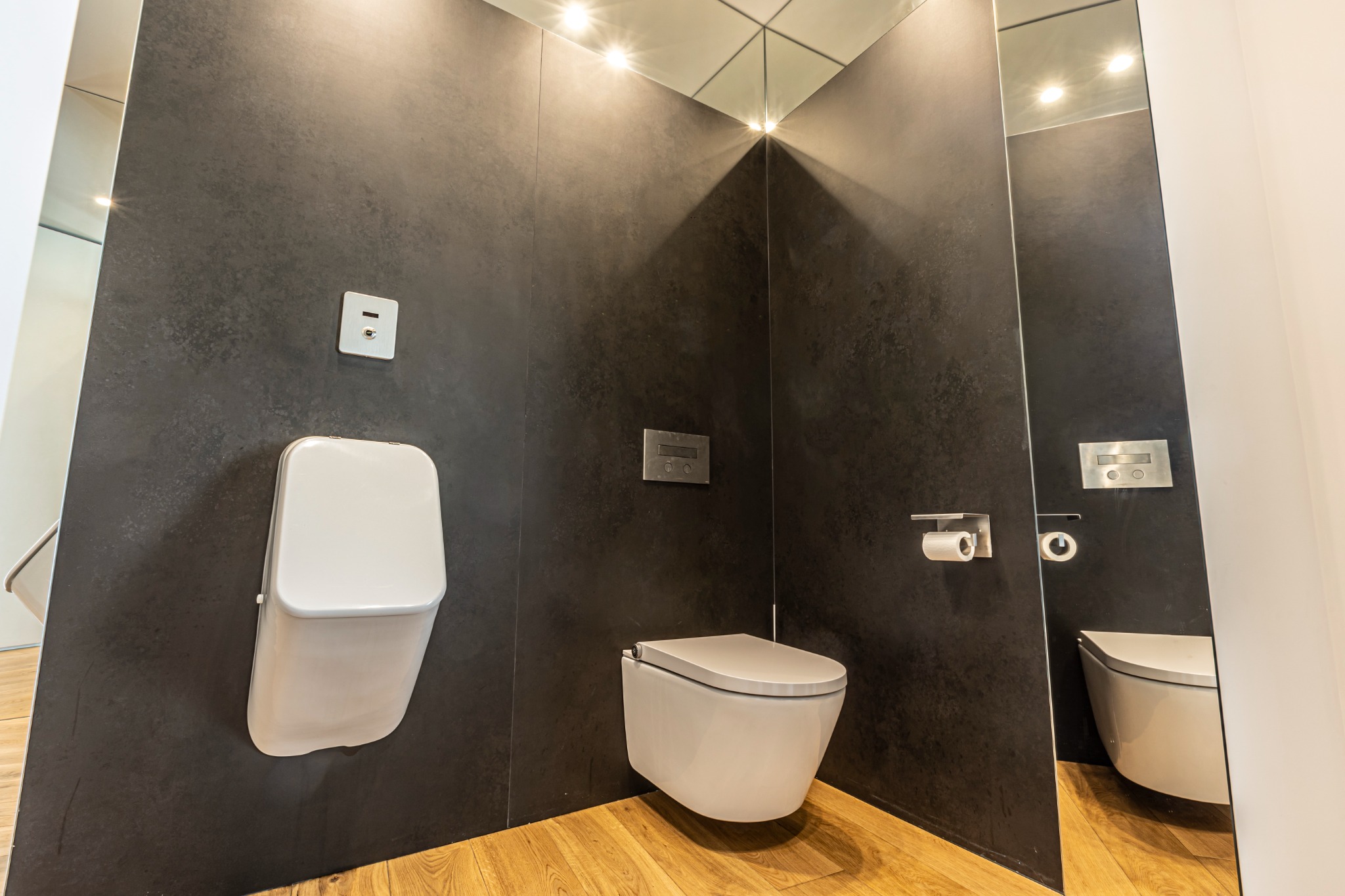 Bagno con rivestimento scuro e sanitari sospesi